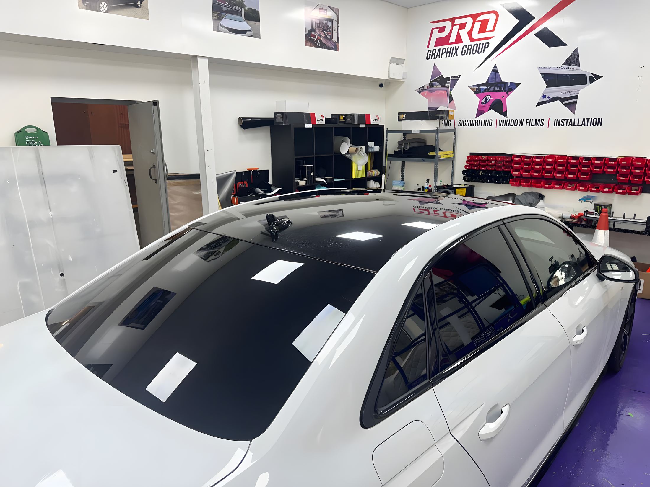 White car with a gloss black roof wrap inside the Pro Graphix unit